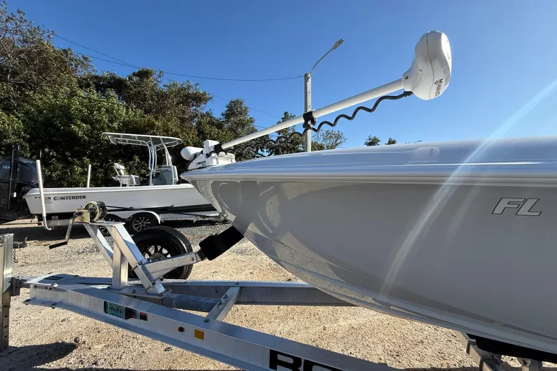 Slide: The Image of 2024 Contender 25 Bay boat on trailer, sunny day, trees in background. - 10