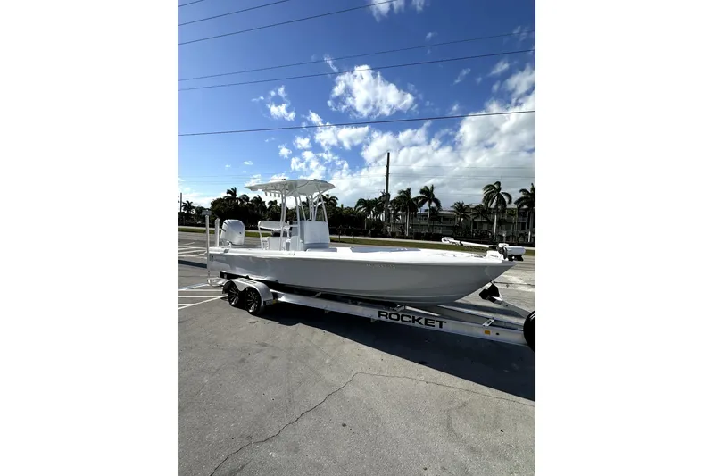 Slide: The Image of 2024 Contender 25 Bay boat interior with white seating and control panel, parked outdoors. - 5