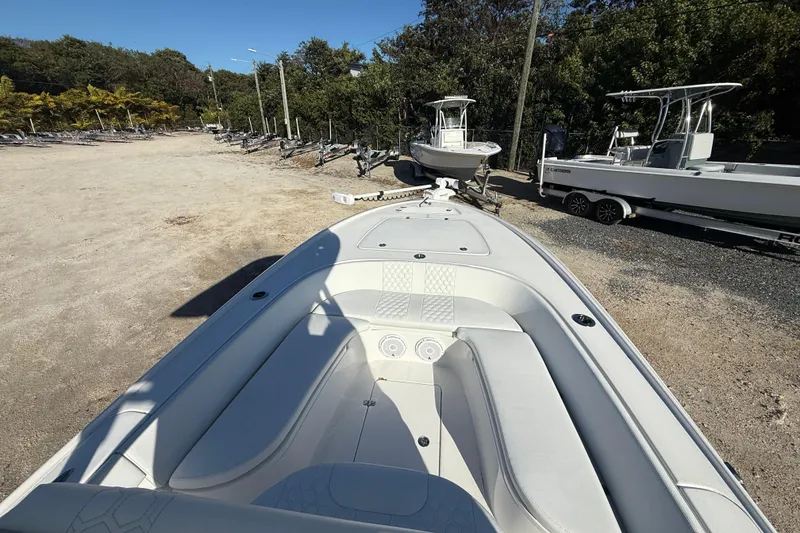 Slide: The Image of 2024 Contender 25 Bay boat on trailer, parked outdoors near trees. - 7