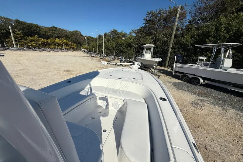 Slide: The Image of 2024 Contender 25 Bay boat on trailer, parked outdoors with trees in the background. - 8