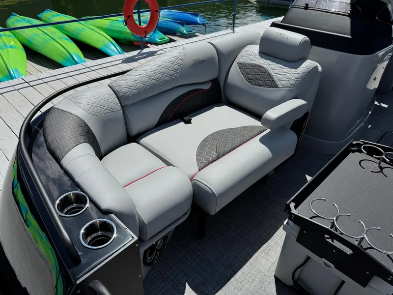 Slide: The Image of Luxurious seating on 2026 JC SportToon 24 TT DSL pontoon boat, docked with kayaks nearby. - 4
