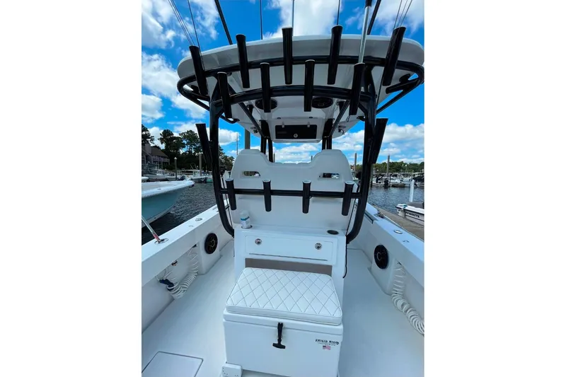 Slide: The Image of 2024 Onslow Bay 33 Tournament boat interior with rod holders and seating, docked at marina. - 12