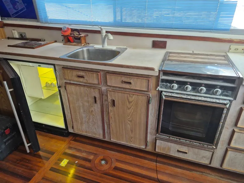Slide: The Image of 1982 Bertram 38 Convertible kitchen with sink, stove, and open mini fridge. - 14