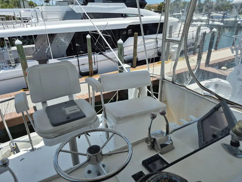 Slide: The Image of 1982 Bertram 38 Convertible yacht cockpit with steering wheel and controls, docked at marina. - 28