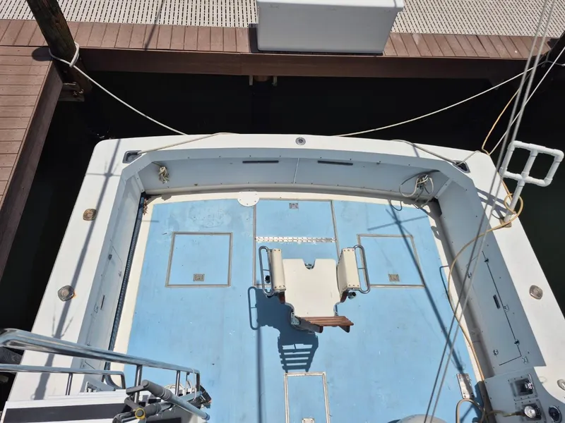 Slide: The Image of 1982 Bertram 38 Convertible boat deck with blue flooring, docked at a marina. - 5