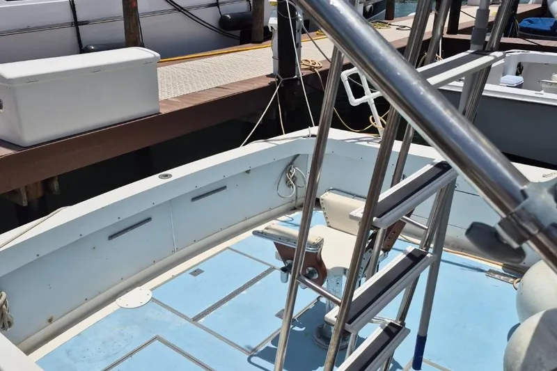 Slide: The Image of 1982 Bertram 38 Convertible boat deck with ladder and seating at marina. - 6