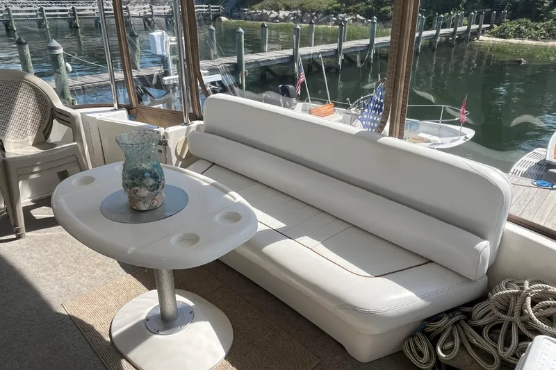 Slide: The Image of 1997 Sea Ray 420 Aft Cabin interior with white seating, table, and marina view. - 10