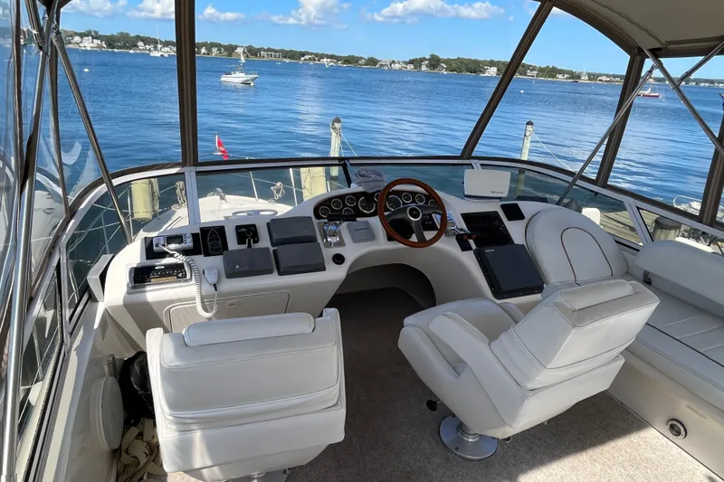Slide: The Image of 1997 Sea Ray 420 Aft Cabin helm with white seating, overlooking serene waters. - 14