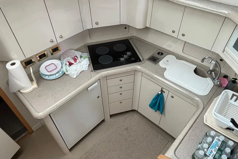Slide: The Image of 1997 Sea Ray 420 Aft Cabin kitchen with stove, sink, and storage cabinets. - 28
