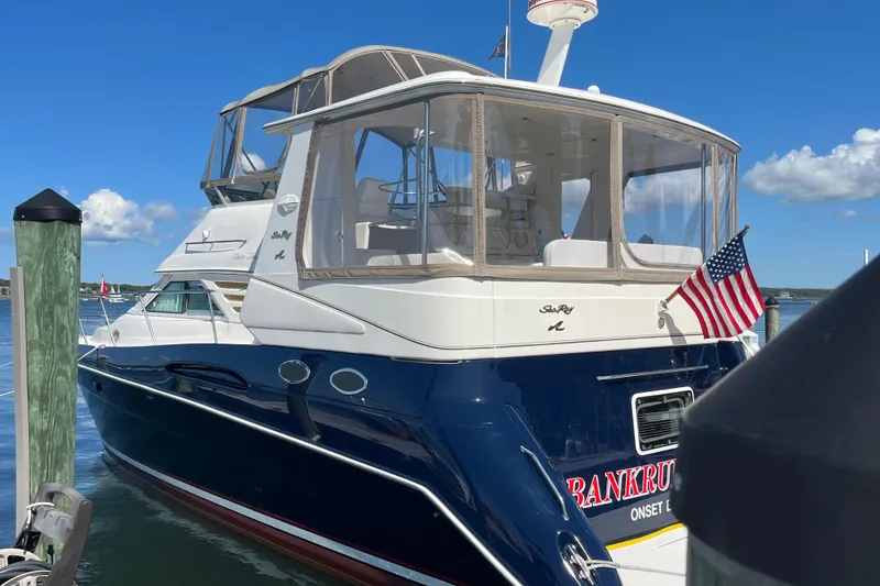 Slide: The Image of 1997 Sea Ray 420 Aft Cabin yacht docked, featuring American flag and clear skies. - 3