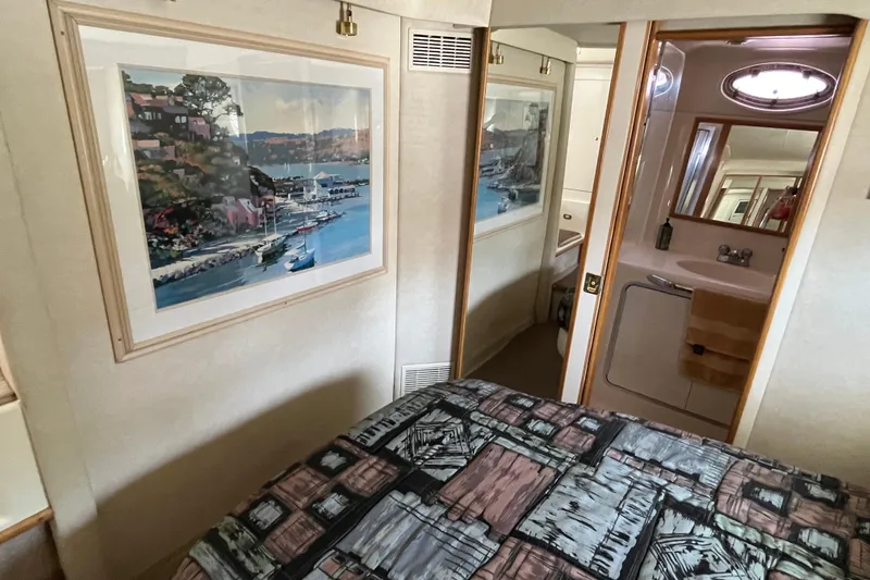 Slide: The Image of 1997 Sea Ray 420 Aft Cabin interior with artwork, bed, and bathroom view. - 46