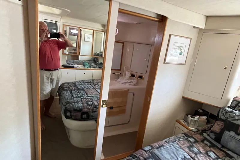 Slide: The Image of 1997 Sea Ray 420 Aft Cabin interior with bed, mirror, and bathroom view. - 47