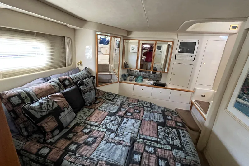 Slide: The Image of Luxurious 1997 Sea Ray 420 Aft Cabin bedroom with patterned bedding and built-in storage. - 50
