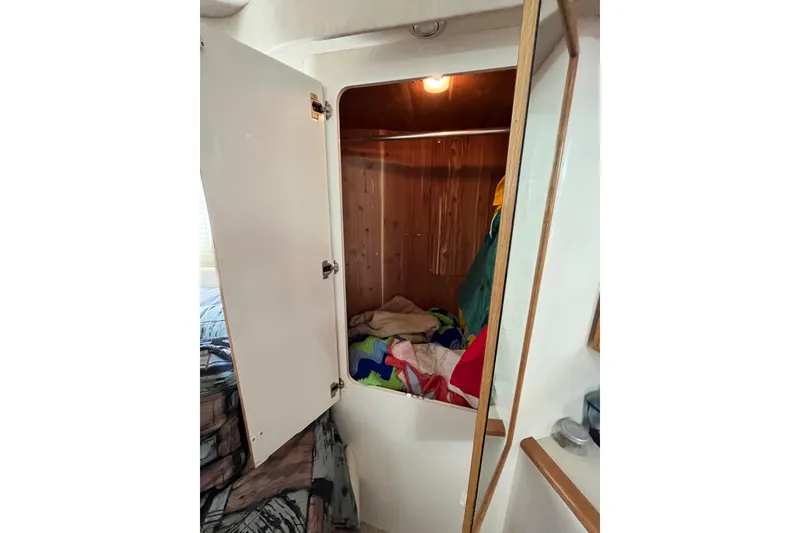 Slide: The Image of Open closet in 1997 Sea Ray 420 Aft Cabin, displaying colorful clothing and wooden interior. - 51