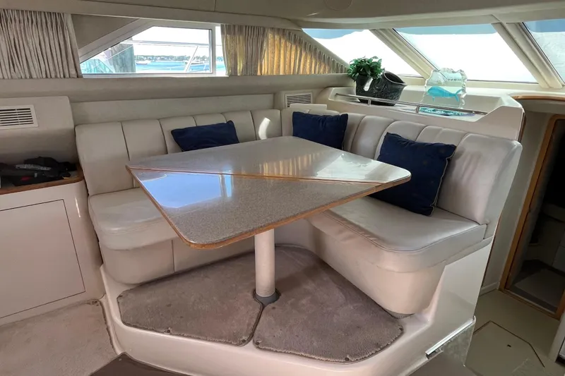 Slide: The Image of 1997 Sea Ray 420 Aft Cabin interior with dining area, white seating, and blue cushions. - 62
