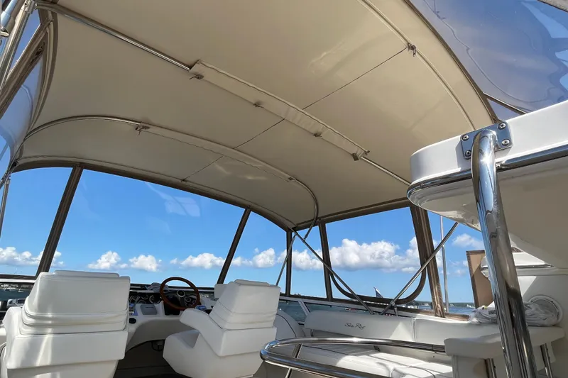 Slide: The Image of 1997 Sea Ray 420 Aft Cabin interior with helm, white seating, and clear blue sky. - 66