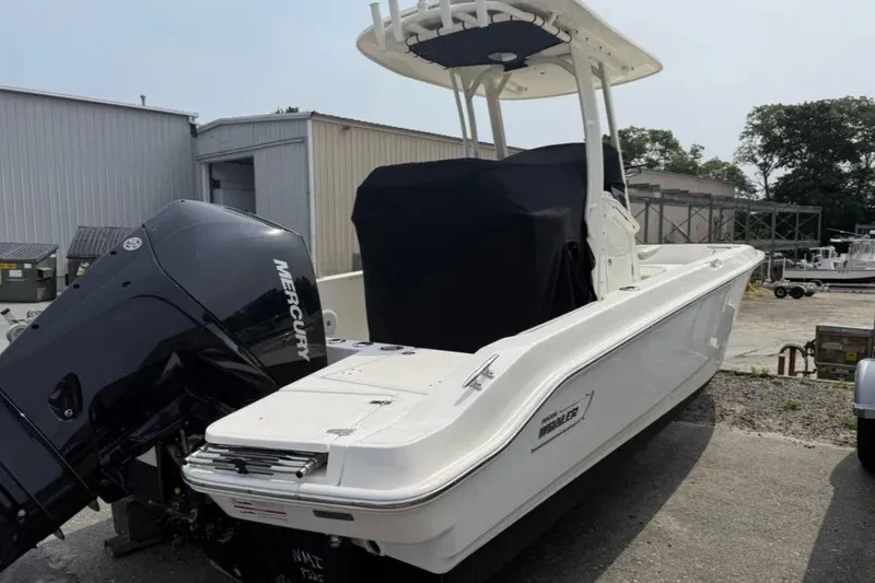 Slide: The Image of 2024 Boston Whaler 220 Dauntless boat with Mercury engine, parked outdoors. - 2