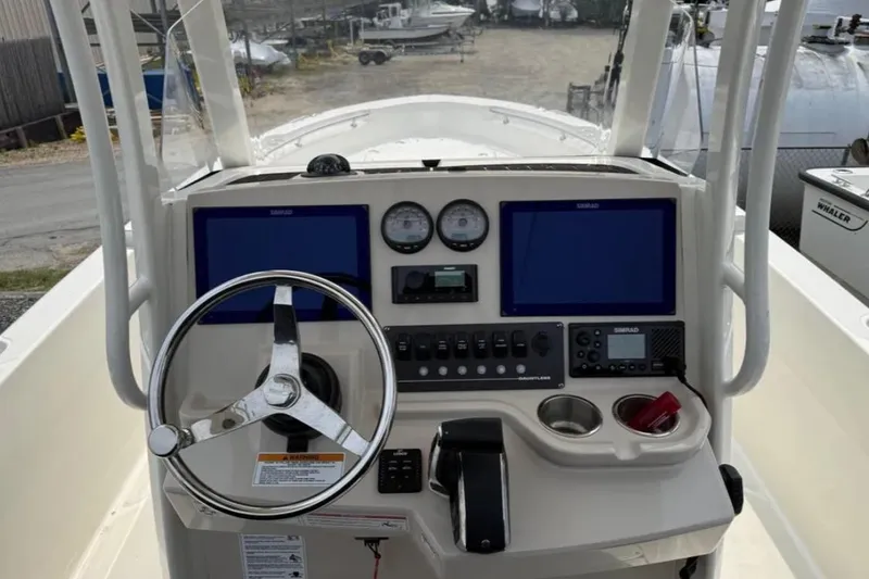 Slide: The Image of 2024 Boston Whaler 220 Dauntless boat dashboard with steering wheel and navigation controls. - 6