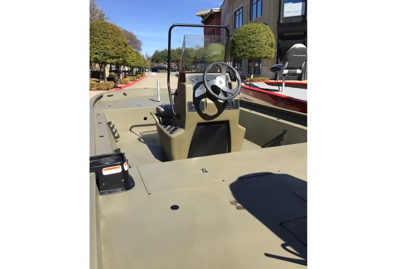 Slide: The Image of 2023 Tracker Grizzly 1860 CC boat interior with steering console, outdoors. - 3