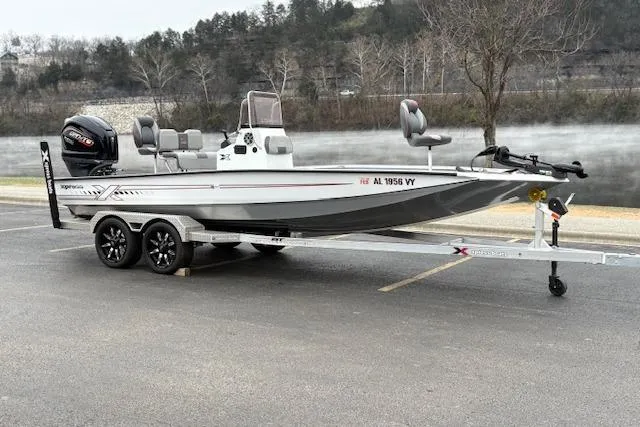 Slide: The Image of 2024 Express H22B boat on trailer, parked by a misty lake with trees in the background. - 10