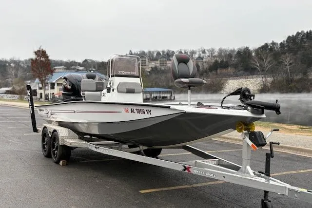 Slide: The Image of 2024 Express H22B boat on trailer, parked outdoors near a lake. - 2