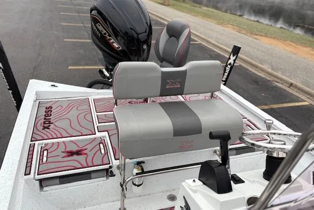 Slide: The Image of 2024 Express H22B boat interior with seating, steering wheel, and motor, parked near water. - 32