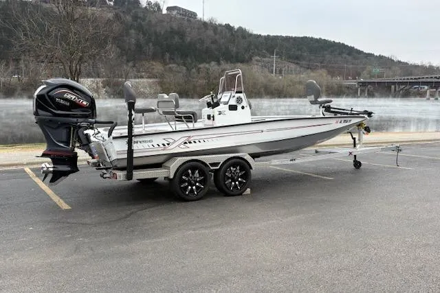 Slide: The Image of 2024 Express H22B boat on trailer, parked near a scenic lake with hills in the background. - 6