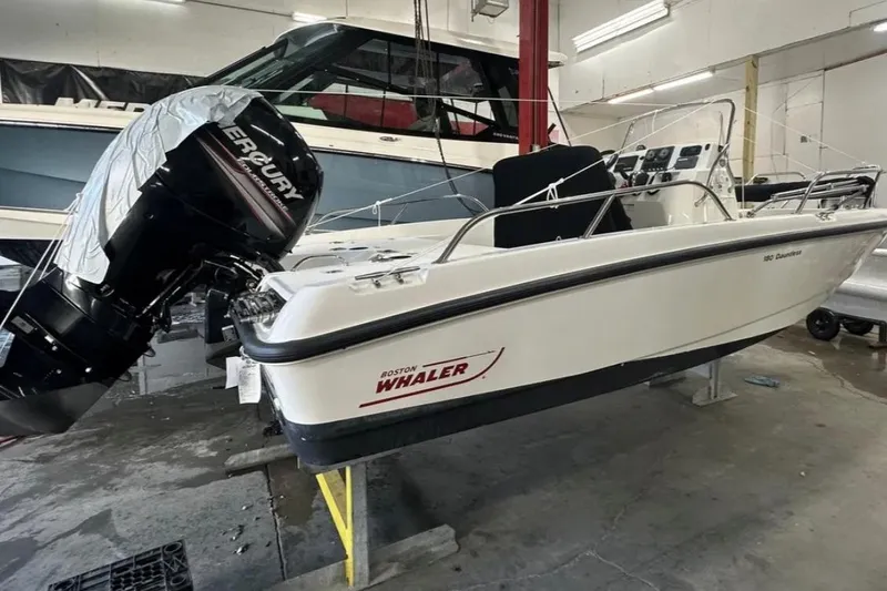 The Image of 2012 Boston Whaler 180 Dauntless boat with Mercury engine in a workshop setting. - 1