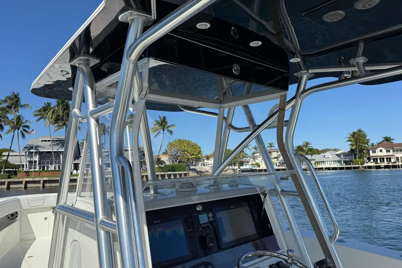 Slide: The Image of 2018 SeaVee 390Z boat console with T-top, docked near waterfront homes. - 18