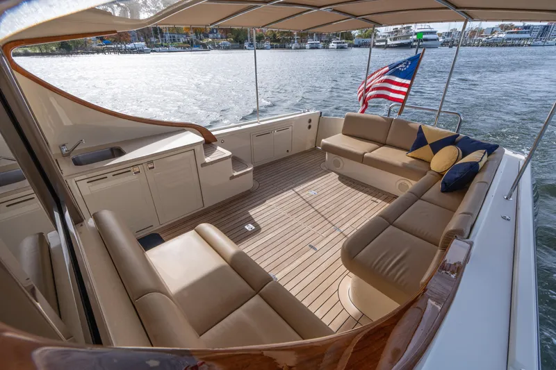 Slide: The Image of 2016 Palm Beach Motor Yachts PB50 interior with seating, American flag, and waterfront view. - 31
