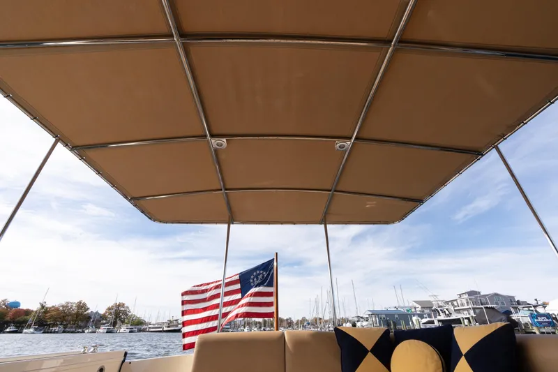Slide: The Image of 2016 Palm Beach Motor Yachts PB50 with canopy, American flag, and marina view. - 33