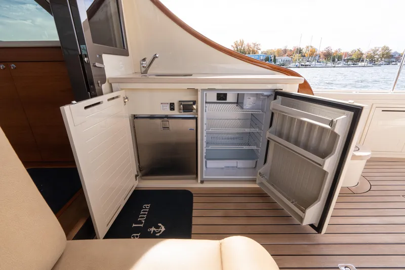 Slide: The Image of 2016 Palm Beach Motor Yachts PB50 with canopy, American flag, and marina view. - 34