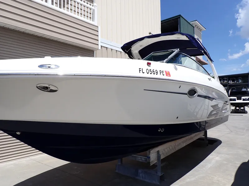 Slide: The Image of 2011 Chaparral 287 SSX boat on display, white and blue exterior, docked outdoors. - 2