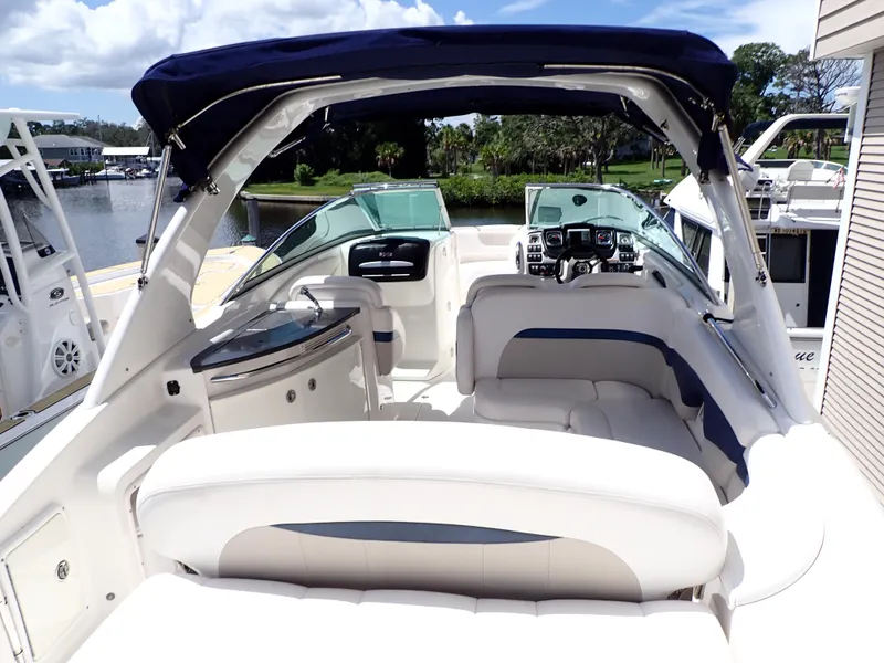 Slide: The Image of 2011 Chaparral 287 SSX boat interior with white seating and blue accents, docked by a serene lake. - 4