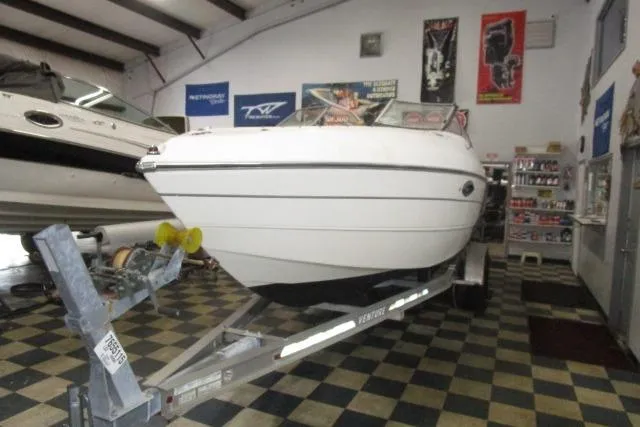 The Image of 2004 Stingray 240 LR boat on trailer in showroom with checkered floor. - 1