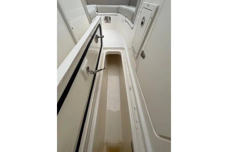 Slide: The Image of 2022 Boston Whaler 240 Vantage interior storage compartment, white finish, open hatch. - 24