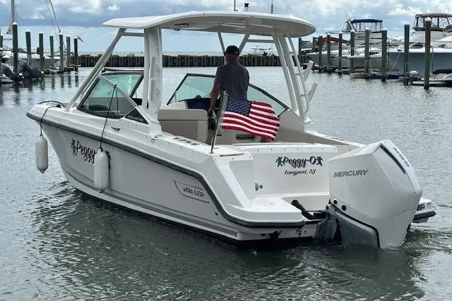 Slide: The Image of 2022 Boston Whaler 240 Vantage boat with American flag, docked in a marina. - 4