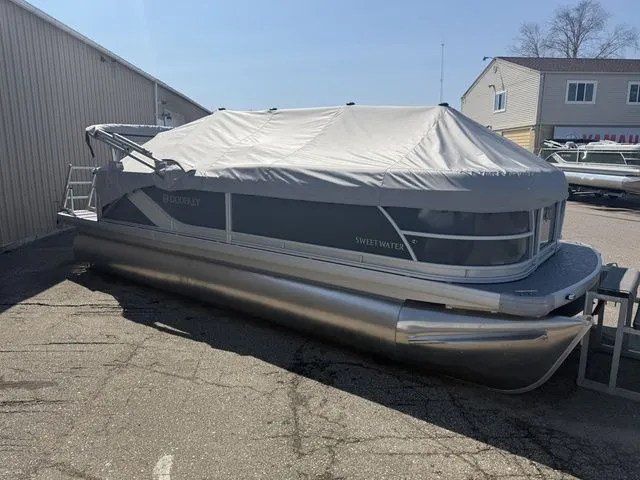 The Image of 2026 Sweetwater SW2086CPSE pontoon boat with cover in parking lot. - 1