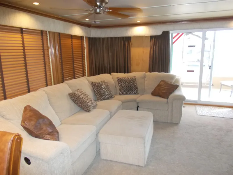 Slide: The Image of 2005 Sumerset Lake Bumz houseboat interior with beige sectional sofa and sliding glass door. - 12