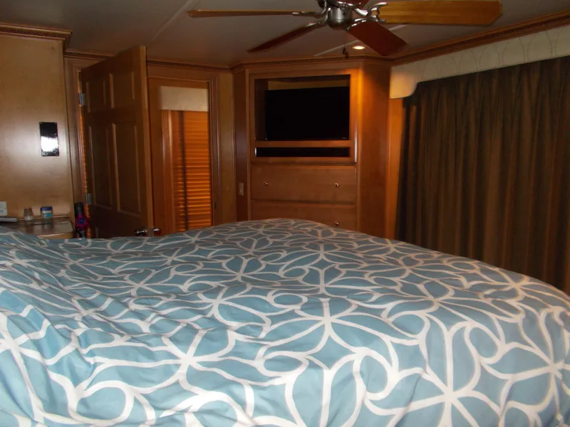 Slide: The Image of Sumerset Lake Bumz 2005 houseboat bedroom with TV, ceiling fan, and patterned bedspread. - 30