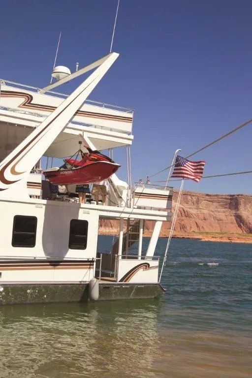 Slide: The Image of 2005 Sumerset Lake Bumz houseboat with jet ski and American flag on lake. - 5
