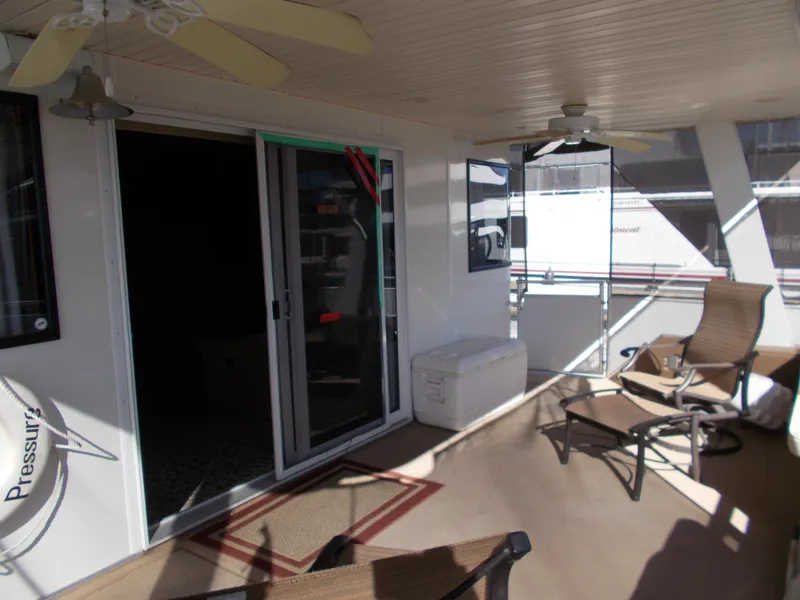 Slide: The Image of 2005 Sumerset Lake Bumz houseboat deck with sliding doors, ceiling fans, and outdoor seating. - 9