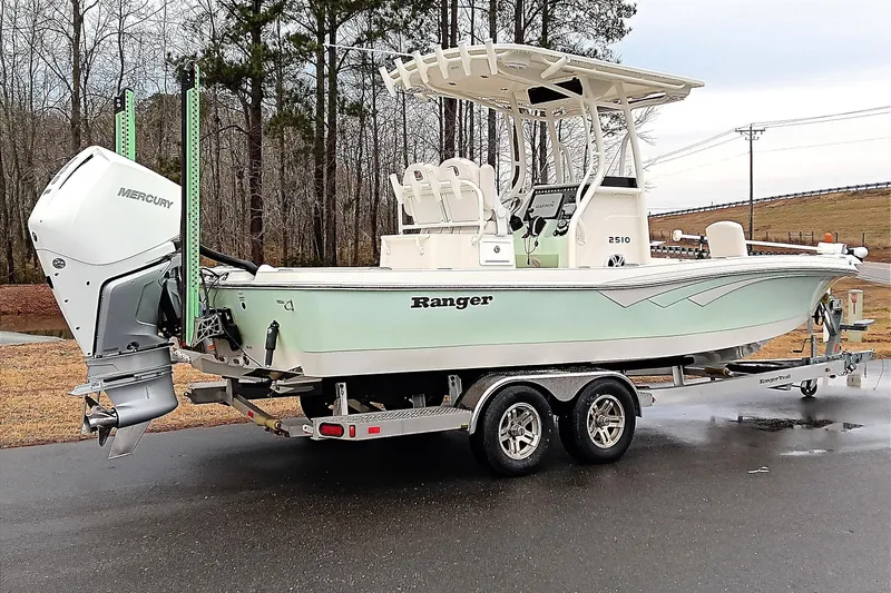 Slide: The Image of 2022 Ranger 2510 Bay boat on trailer with Mercury engine, parked outdoors. - 2