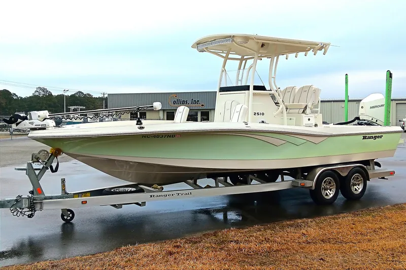 Slide: The Image of 2022 Ranger 2510 Bay boat on trailer, parked outdoors near Collins Inc. building. - 6