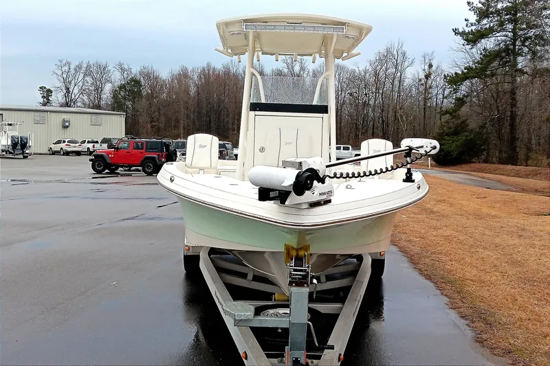 Slide: The Image of 2022 Ranger 2510 Bay boat on trailer in parking lot, surrounded by trees and vehicles. - 7