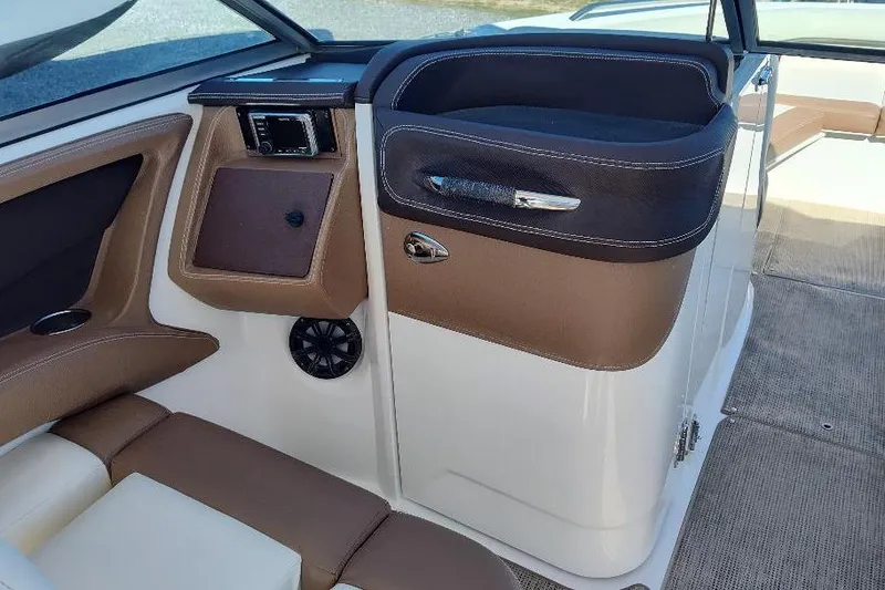 Slide: The Image of 2016 Cobalt 302 boat interior with brown and white seating, modern dashboard, and speaker. - 15