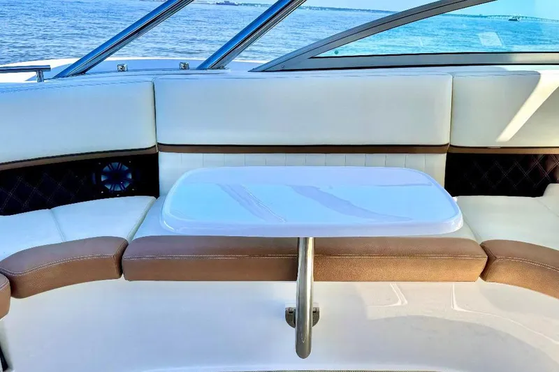 Slide: The Image of 2016 Cobalt 302 boat interior with white and brown seating, table, and ocean view. - 21