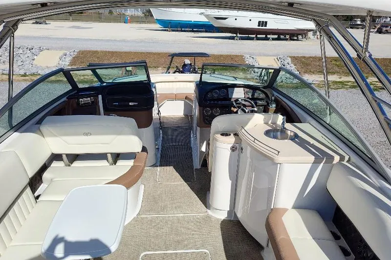 Slide: The Image of 2016 Cobalt 302 boat interior with seating, helm, and sink, docked on a sunny day. - 23