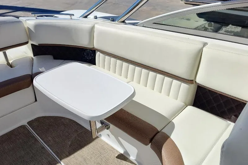 Slide: The Image of 2016 Cobalt 302 boat interior with white and brown seating, small table. - 27