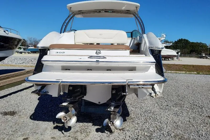 Slide: The Image of 2016 Cobalt 302 boat rear view with dual propellers on gravel surface. - 6